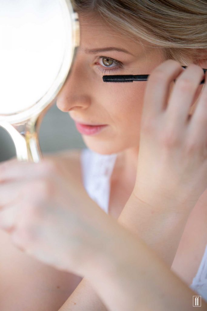 Eine Braut trägt sich bei der Vorbereitung Wimperntusche auf