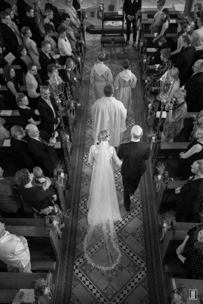 Braut wird von ihrem Vater zum Altar geführt. Wir sehen sie von oben